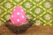 Pink dyed big easter egg in a bird nest on a wooden table