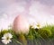 Pink easter egg with flowers in tall grass