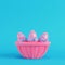 Pink easter eggs with bow in a wicker basket on bright blue background in pastel colors
