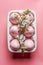 Pink Easter eggs in white egg holder with white cherry blossom  on pink background. Seasonal springtime setting. Top view
