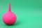 Pink enema on green background, space for text. Medical treatment