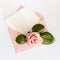 Pink envelop with white card and rose. Flat lay.