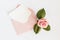 Pink envelop with white card and rose. Flat lay.