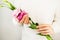 Pink eustoma flower in woman`s hands. Lady in white sweater closeup. Feminine floral background