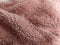 Pink faux fur folded in waves. Pale dirty pink color of synthetic material. Soft texture that you want to touch and stroke. Woolen