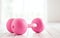 pink female dumbbells and ball on a light wooden floor on light sports hall background