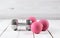 pink female dumbbells and ball on a light wooden floor on light sports hall background