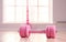 pink female dumbbells and a skipping rope on a light wooden floor on light sports hall background