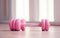 pink female dumbbells and a skipping rope on a light wooden floor on light sports hall background