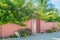 Pink fence with gateway leading to house in the village at tropical island