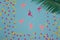pink flamingos on a pastel blue background with colorful chopped paper part, palm leaf in the corner