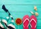 Pink flip flops, shells and summer swim suit with candy and copy space on blue wooden background. Top view