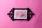 Pink floral bloom in black ornate frame on pink backdrop with copy space
