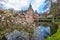 Pink flowering plants with the castle of Het Oude Loo with its moat with reflection in the water and its bridge in the background