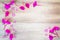 Pink flowers formed as border with hearts on vintage grunge wooden background