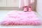 pink fluffy slippers on a shaggy white bathroom mat