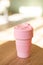 Pink foldable silicone cup for drinks without plastic in the style of zero waste on a interior background, close-up. Product