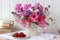 Pink garden flowers, raspberries and currants on the table on a light background