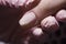Pink gel polish runs down the nail plate. The manicurist applies a layer of gel polish to the client`s nail.