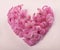 Pink geocynth flowers are laid out in the form of a heart. ornament of spring flowers on a pink background