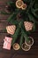 Pink gift box with cones, spruce branches, cookies shaped christmas tree and dry slices of citrus on a dark wooden background.