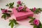 Pink gift box with rosehip flowers, side view