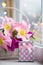 Pink gift box and tender bouquet of beautiful pink tulips in white basket near window with raindrops in the daylight