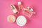Pink glass perfume bottles, facial cream and some cosmetic and makeup products on pink background. Bottle of female