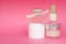 Pink glass perfume bottles, facial cream and some cosmetic and makeup products on pink background. Bottle of female