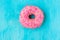 Pink glazed doughnut with sugar sprinkles on light blue background, in the middle, copyspace, template, birthday, card, poste