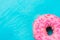 Pink glazed doughnut with sugar sprinkles in right bottom corner on light blue background, copyspace, template, birthday