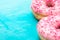 Pink glazed doughnuts with sugar sprinkles on light blue background, copyspace, birthday, card, poster, text ready