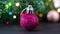 Pink glitter Christmas tree ornament and blinking lights behind