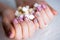 Pink glitter nails with marshmallow candies on woman`s hand. colourful vivid manicure on lady fingers