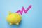 Pink graph rising out of yellow piggy bank on blue background