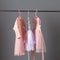 Pink and gray sequined luxury dresses for baby girls hang on hangers on a gray background