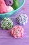 Pink, green and blue crochet flowers decorated with beads. Cotton yarn skeins in basket, hook and bright knitted roses