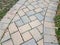 Pink and grey stone tile path with weeds