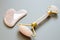 Pink Gua Sha massage tool on a gray background. Rose Quartz roller. Facial skin care at home, anti-aging and lifting therapy.