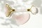 Pink Gua Sha massage tool. Rose Quartz roller. Gray shadow of the leaves on a white background. Facial skin care at home, anti-agi