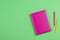 Pink hardcover book and colorful pens on green background