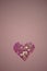 Pink heart made of sequins on a pale deep rose table. Copy space