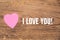 Pink heart post-it with the text `I love you` on a wooden background