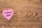 Pink heart post-it with the text `I love you` on a wooden background