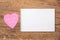 Pink heart post-it with the text `Ich liebe dich` and a notebook on a wooden background. Translation: `I love you`