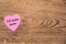 Pink heart post-it with the text `Ich liebe dich` on a wooden background. Translation: `I love you`