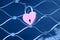 Pink heart-shaped lock on a steel mesh. Romantic declaration of love