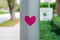 Pink heart-shaped sticker stuck on lamppost