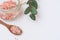 Pink Himalayan salt in glass jar, green eucalyptus branch, wooden spoon on white background, top view