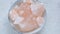 Pink himalayan salt pieces close-up in a gray cup on a marble background.Pink crystal salt